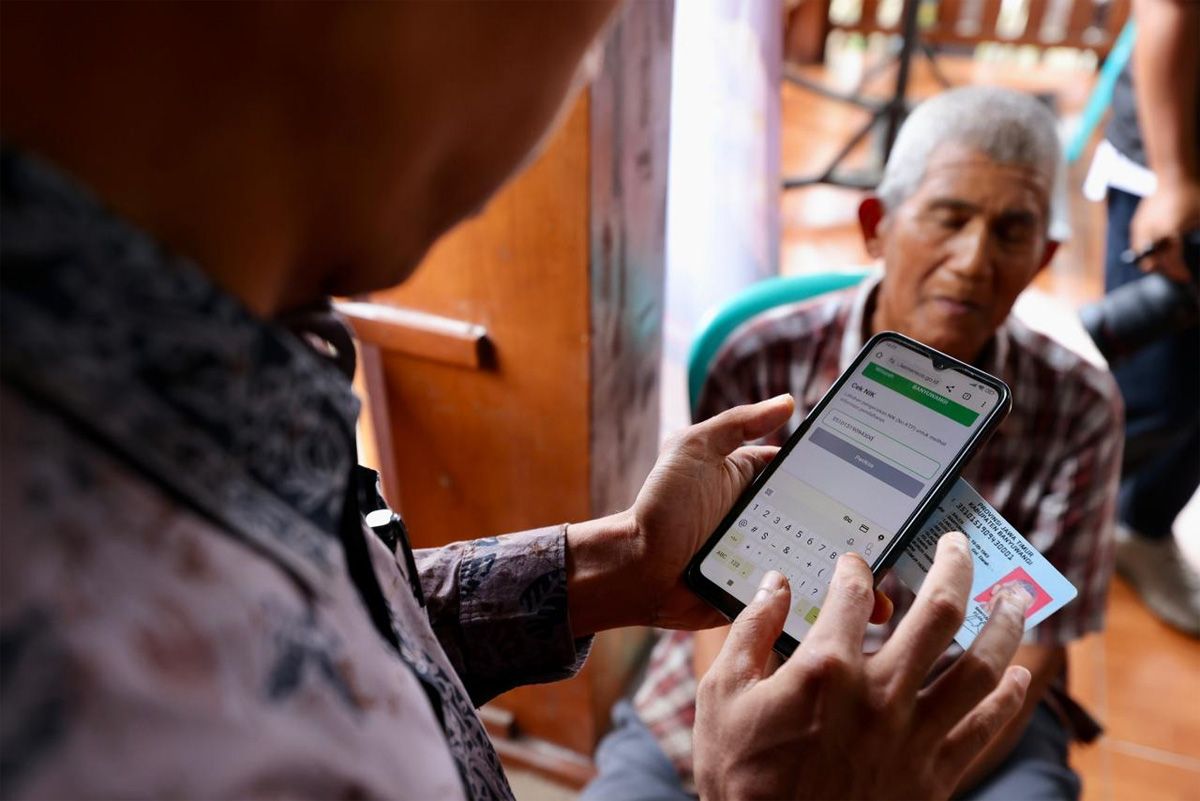 Warga mengecek status penerimaan bansos lewat ponsel